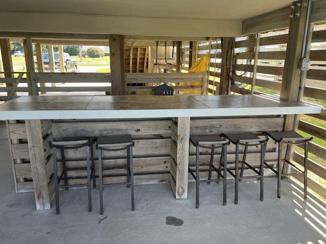 bar with a dry bar and concrete flooring