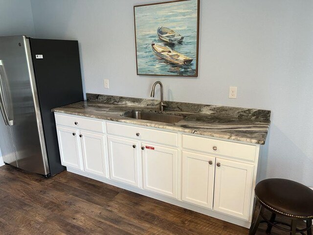 kitchen with freestanding refrigerator, dark wood-style flooring, white cabinetry, and a sink