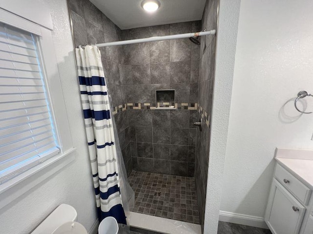 bathroom with toilet, tiled shower, and vanity