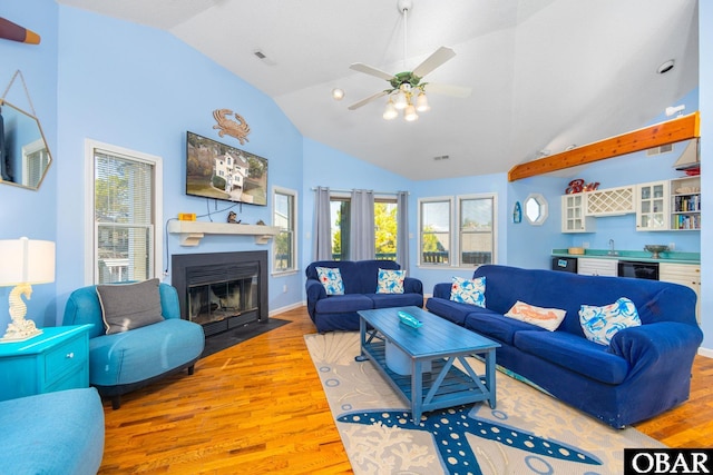 living room with high vaulted ceiling, a fireplace with flush hearth, visible vents, light wood finished floors, and indoor wet bar