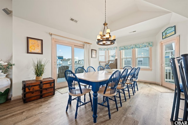 dining space featuring light wood-style flooring, visible vents, and a notable chandelier