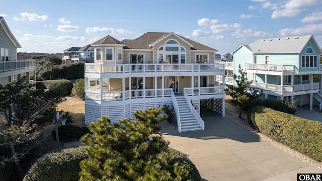 coastal home featuring driveway and stairway