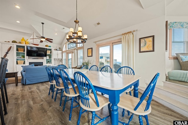 dining area with a fireplace, visible vents, vaulted ceiling, and wood finished floors