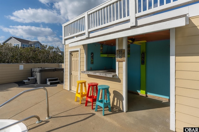 view of patio with outdoor dry bar, a hot tub, and a balcony