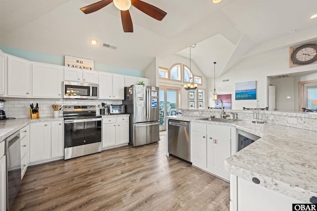 kitchen with visible vents, white cabinets, wood finished floors, stainless steel appliances, and pendant lighting