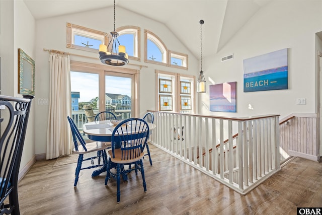 dining room featuring high vaulted ceiling, visible vents, an inviting chandelier, and wood finished floors