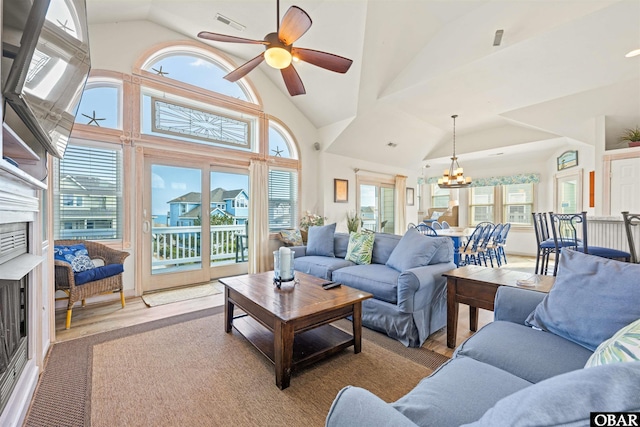 living room with visible vents, high vaulted ceiling, ceiling fan with notable chandelier, and a wealth of natural light