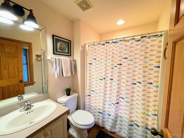 bathroom featuring curtained shower, visible vents, vanity, and toilet