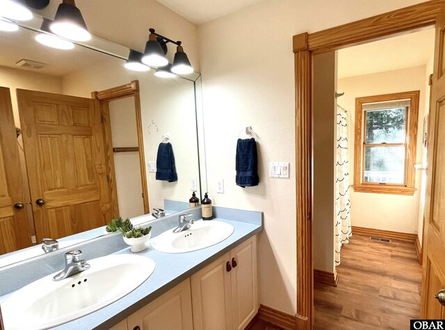 bathroom featuring double vanity, visible vents, a sink, and wood finished floors