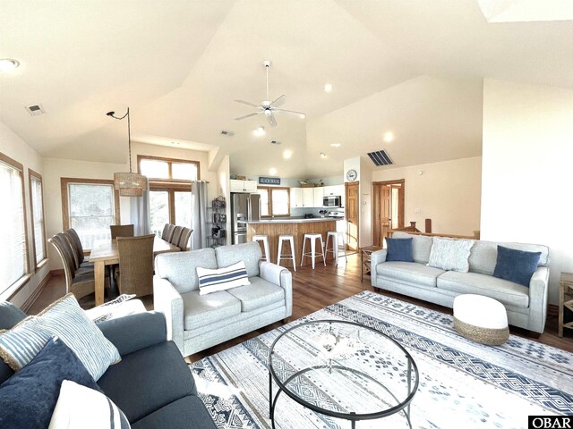 living room with dark wood-style floors, high vaulted ceiling, visible vents, and a ceiling fan