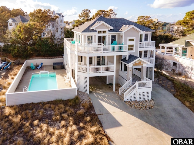 back of house featuring a balcony, stairway, roof with shingles, a residential view, and a fenced in pool