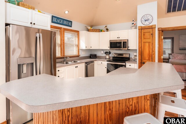 kitchen with appliances with stainless steel finishes, visible vents, and a kitchen bar