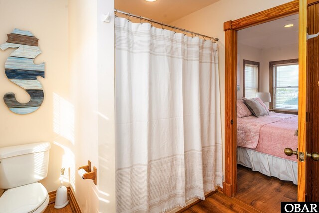 ensuite bathroom with wood finished floors, ensuite bath, and toilet