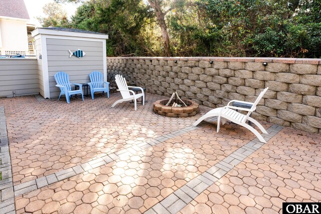 view of patio featuring an outdoor fire pit, an outdoor structure, and a storage shed