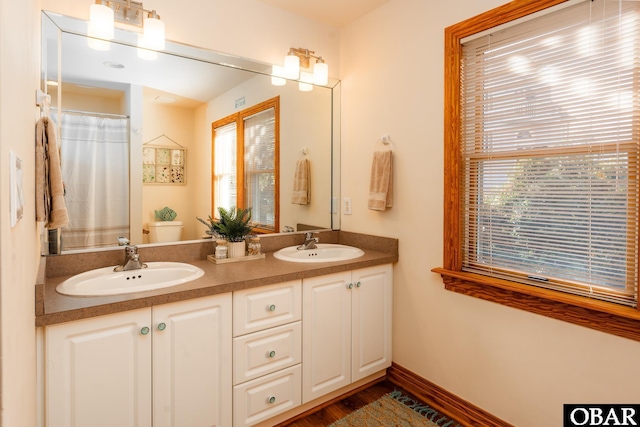 full bath featuring toilet, a sink, baseboards, and double vanity