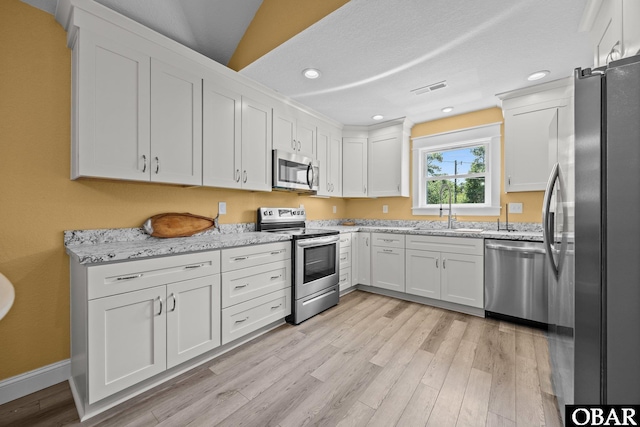 1021 Harbour View Dr Lot 43, Kill Devil Hills, NC 27948 - kitchen with appliances with stainless steel finishes, light wood finished floors, white cabinetry, light stone countertops, and recessed lighting