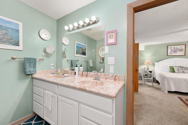 full bath featuring double vanity, a sink, a textured ceiling, and ensuite bathroom