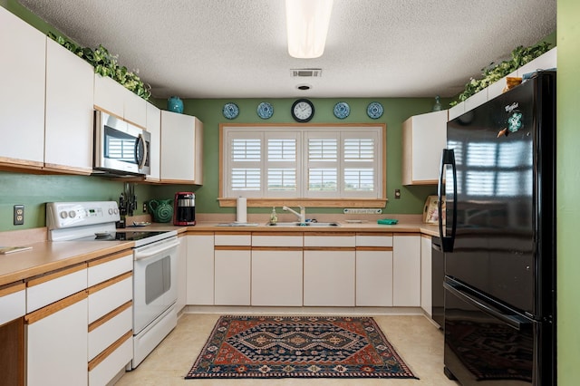 kitchen featuring a sink, visible vents, white cabinets, light countertops, and black appliances