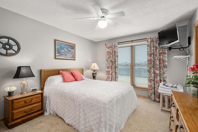 bedroom featuring a ceiling fan, light colored carpet, and a textured ceiling