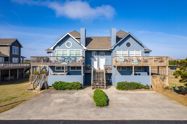 view of front of house featuring stairs, a deck, a chimney, and a balcony