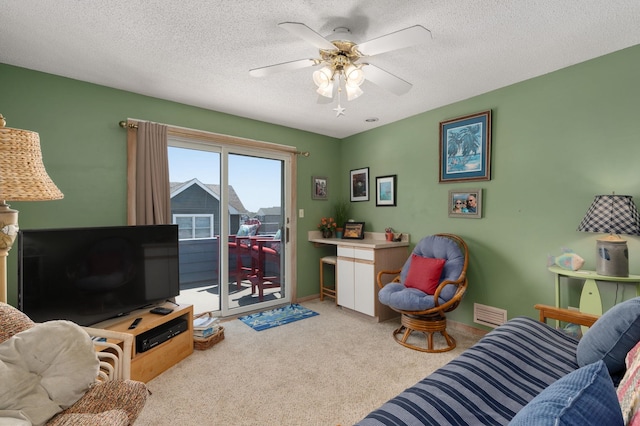 living area featuring a textured ceiling, visible vents, a ceiling fan, and light colored carpet