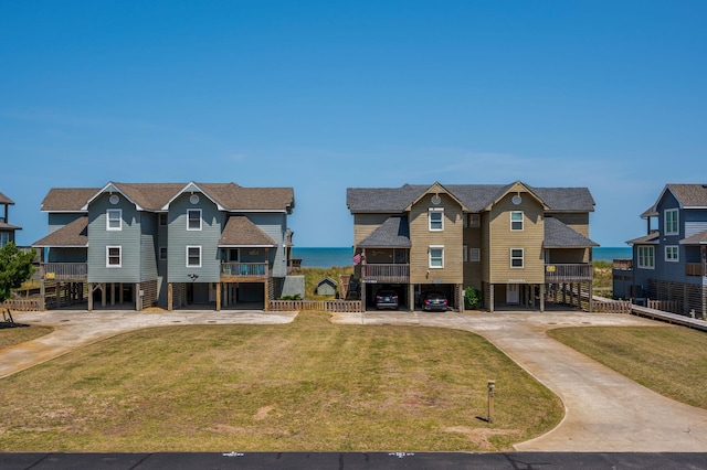 view of front of home with a carport, driveway, a front lawn, and a water view