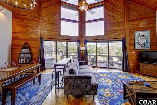 50050 Bayside Ct Lot 30, Frisco, NC 27936 - living room featuring wood walls, a high ceiling, a chandelier, healthy amount of natural light, and ceiling fan