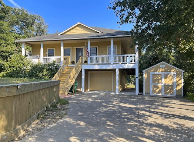 coastal home with a garage, a storage shed, stairs, an outdoor structure, and a porch