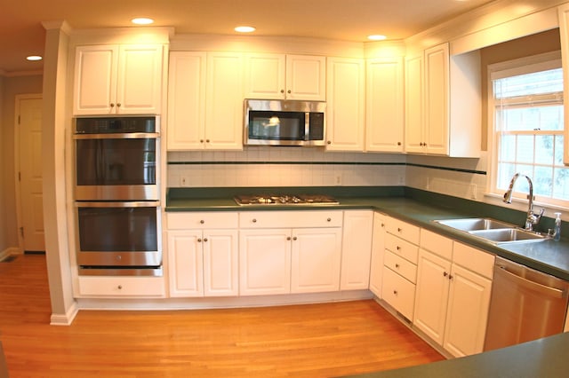 kitchen featuring stainless steel appliances, a sink, and white cabinets