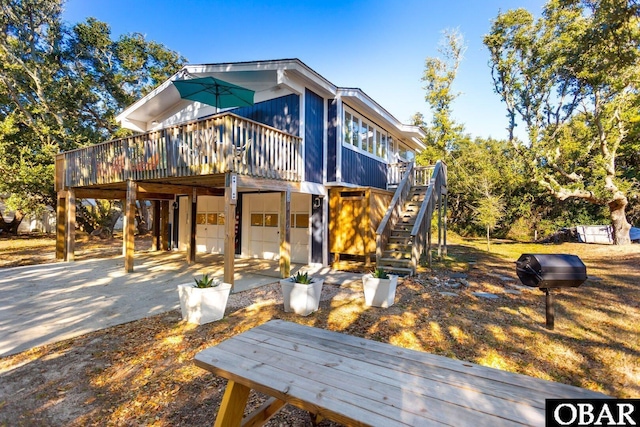 exterior space with a garage, a wooden deck, stairway, and concrete driveway