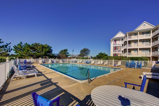 community pool with a patio area and fence