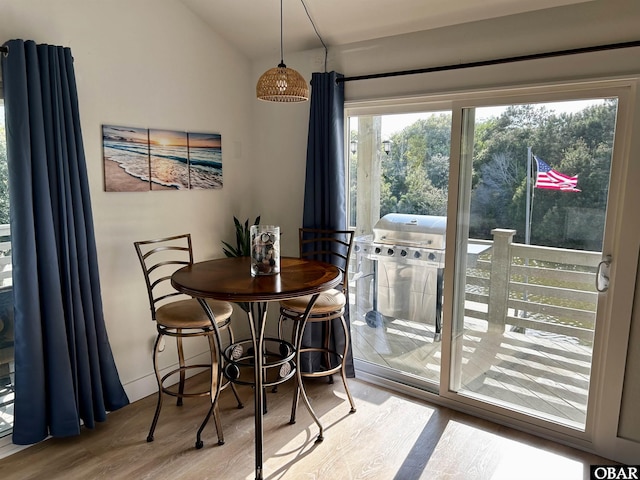 dining space featuring vaulted ceiling and wood finished floors