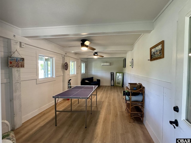 rec room featuring ornamental molding, wainscoting, wood finished floors, beamed ceiling, and ceiling fan