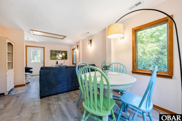 dining area featuring baseboards, a textured ceiling, visible vents, and wood finished floors