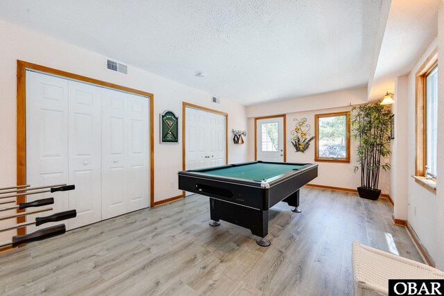 recreation room with a textured ceiling, light wood-type flooring, and visible vents