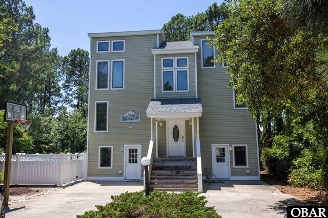 view of front facade featuring concrete driveway and fence