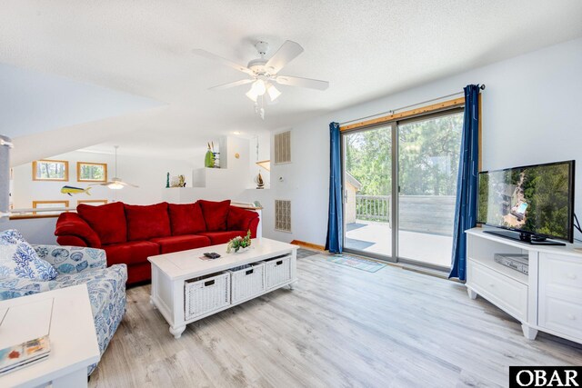 living area featuring a textured ceiling, light wood-type flooring, visible vents, and a ceiling fan