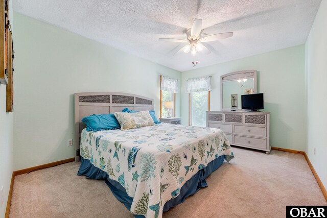 bedroom featuring light carpet, a ceiling fan, baseboards, and a textured ceiling