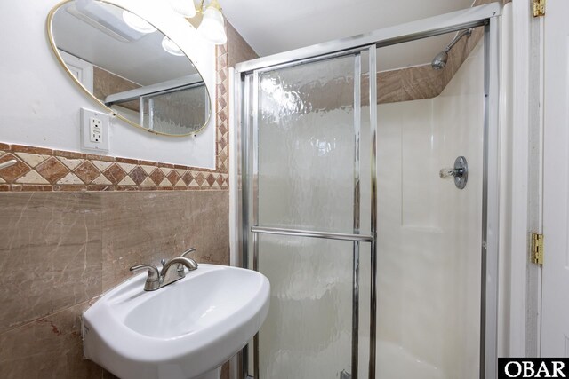 bathroom featuring a shower stall, tile walls, and a sink