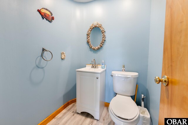 half bathroom featuring toilet, baseboards, wood finished floors, and vanity