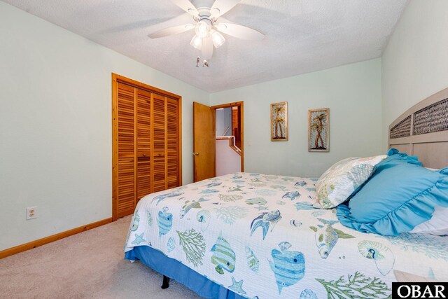 carpeted bedroom with a ceiling fan, a textured ceiling, baseboards, and a closet