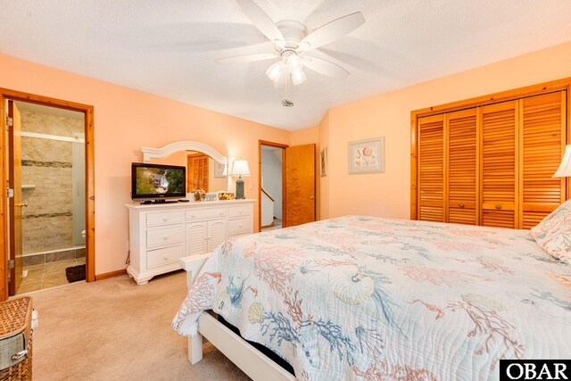 bedroom with baseboards, light colored carpet, ceiling fan, ensuite bathroom, and a closet