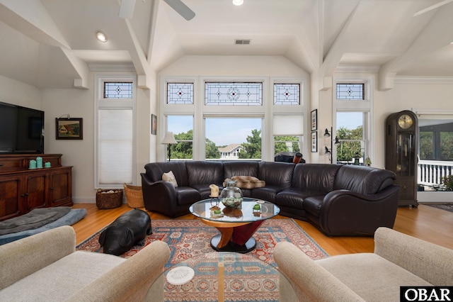 living area featuring a towering ceiling, light wood-style floors, visible vents, and a ceiling fan