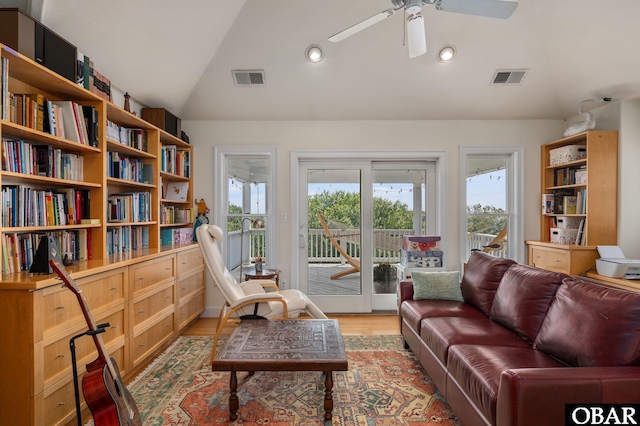 living area featuring plenty of natural light, visible vents, and vaulted ceiling