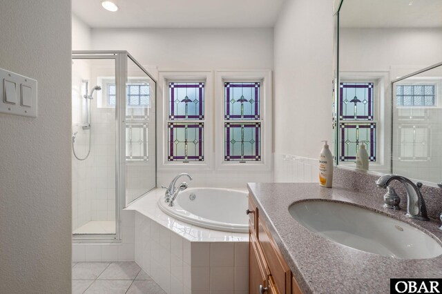 bathroom featuring vanity, a healthy amount of sunlight, a bath, tile patterned floors, and a stall shower