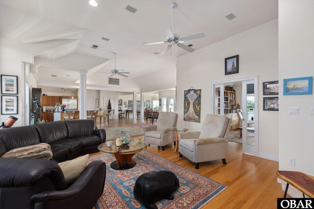 living area featuring visible vents, ceiling fan, decorative columns, and light wood-style flooring