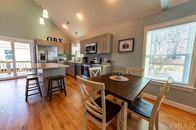 dining room with high vaulted ceiling, light wood-type flooring, visible vents, and baseboards