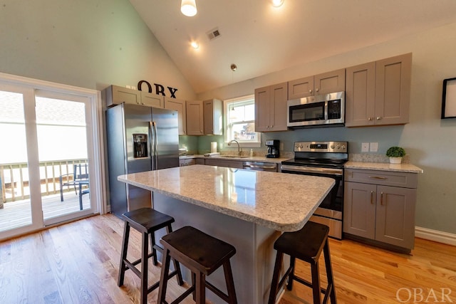 kitchen featuring stainless steel appliances, gray cabinets, a sink, and a kitchen island