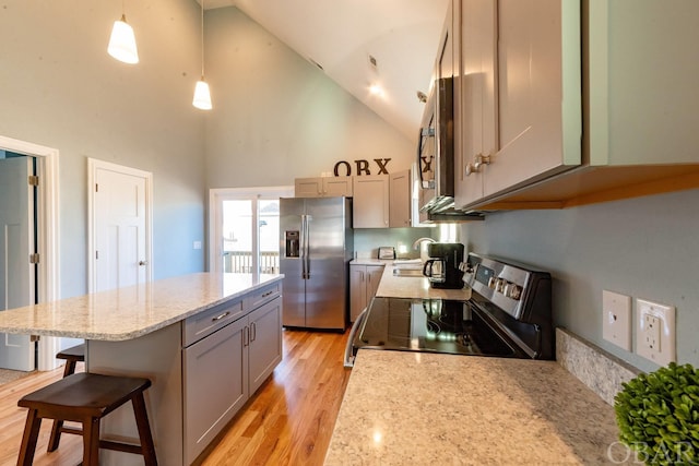 kitchen featuring a breakfast bar, stainless steel appliances, hanging light fixtures, light wood-style flooring, and a kitchen island