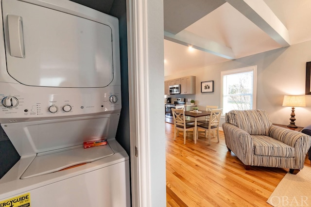 laundry area with laundry area, light wood-type flooring, and stacked washer and clothes dryer